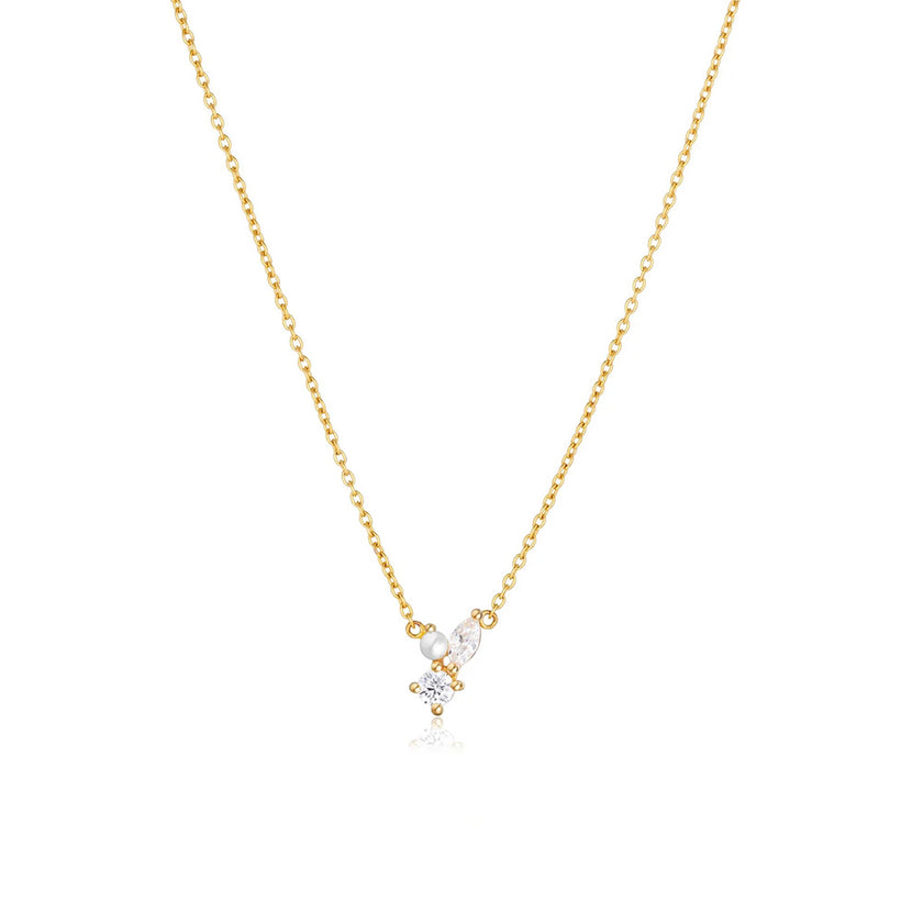 A gold chain necklace with a pearl and clear stone detailing on the pendant.