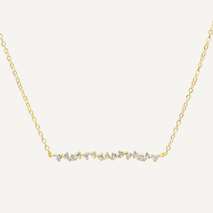 Gold necklace with small diamonds on a light gray background
