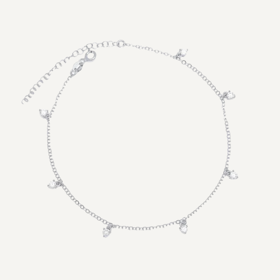 Silver anklet with small charms on a light gray background