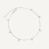 Silver anklet with small charms on a light gray background
