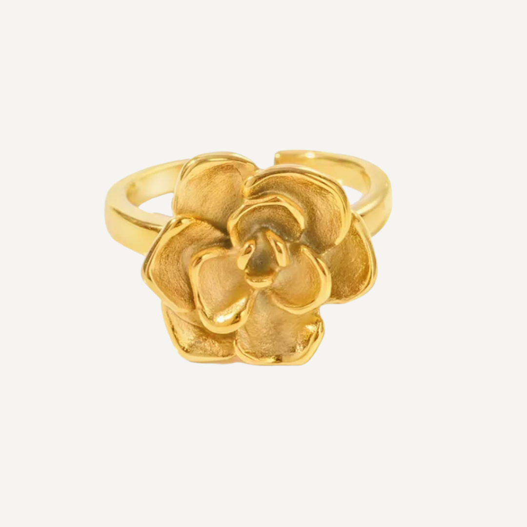Gold flower-shaped ring on a light gray background