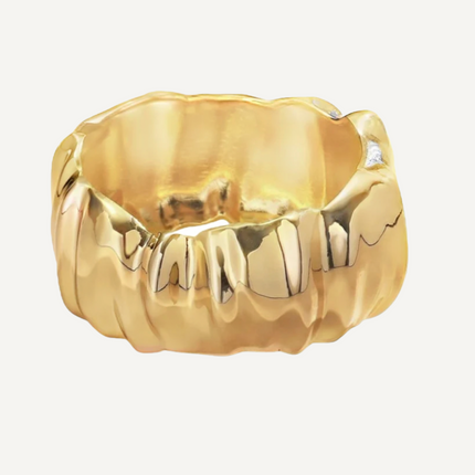 Gold bangle with a unique design on a light gray background