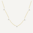 Gold necklace with diamond pendants on a light beige background