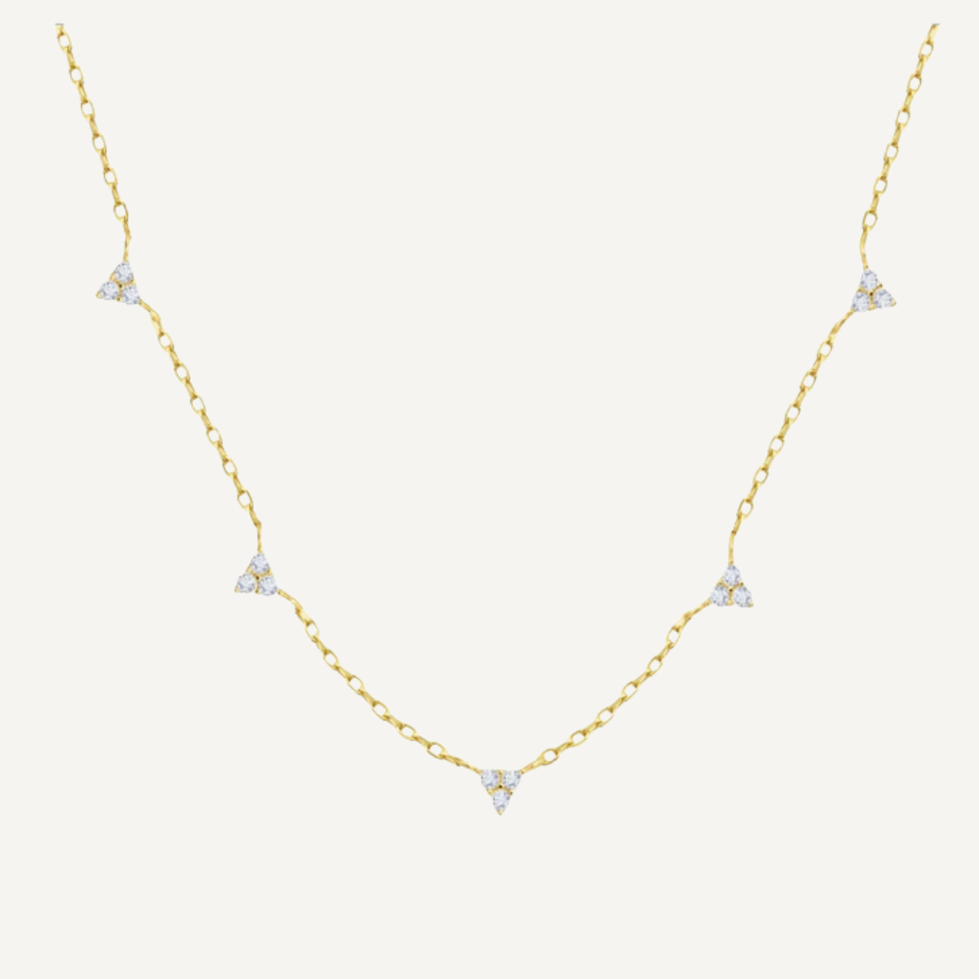 Gold necklace with diamond pendants on a light beige background
