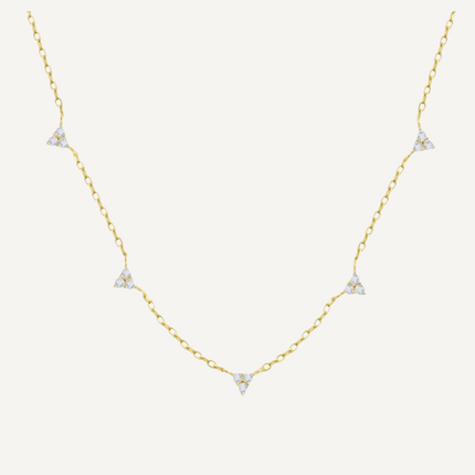Gold necklace with diamond pendants on a light beige background