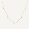 Gold necklace with diamond pendants on a light beige background