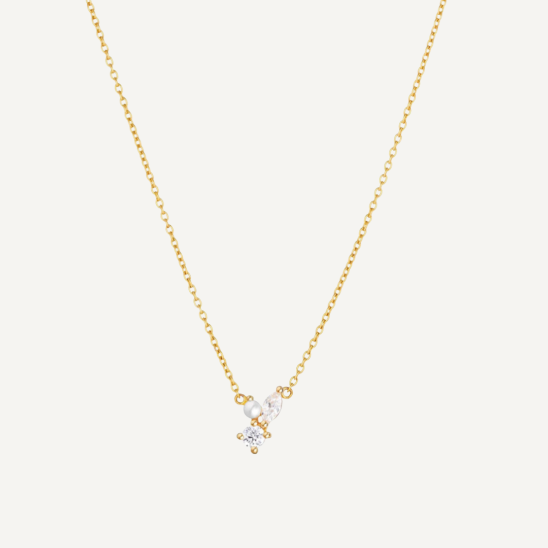 Gold necklace with a small pendant on a light gray background