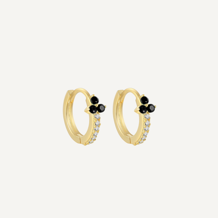 Gold hoop earrings with black and clear gemstones on a light gray background