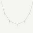 Delicate silver necklace with small pendants on a light gray background