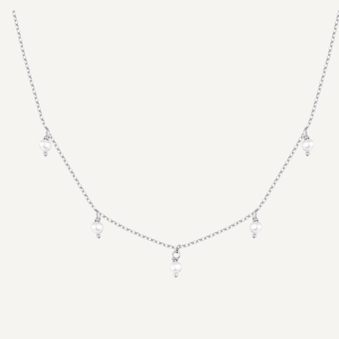 Delicate silver necklace with small pendants on a light gray background