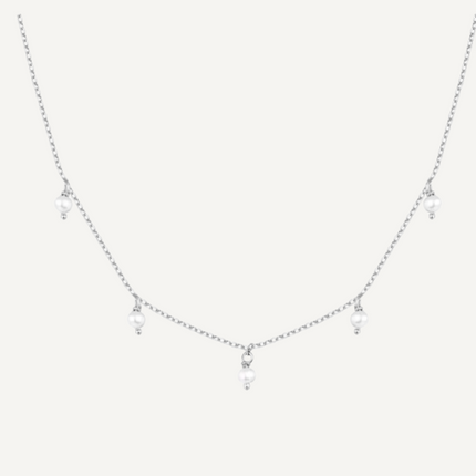 Delicate silver necklace with small pendants on a light gray background