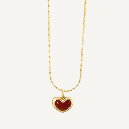 Gold necklace with a red heart pendant on a white background
