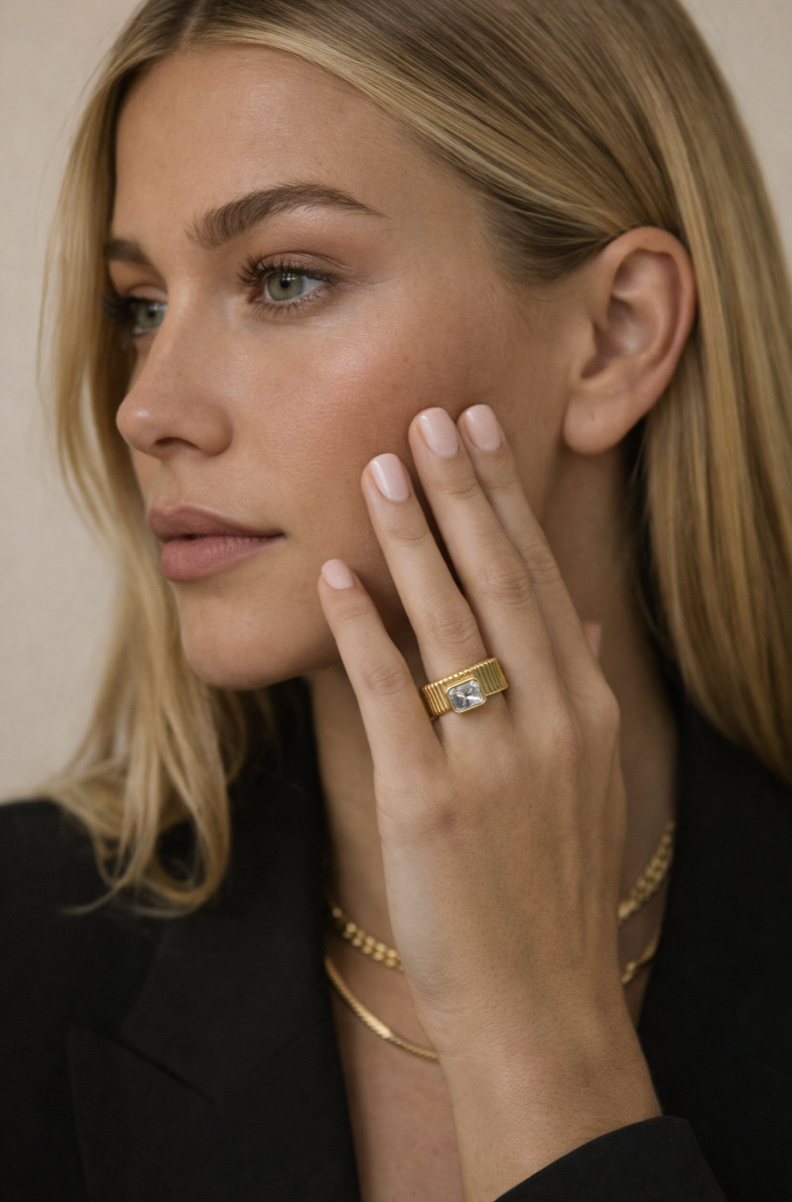 Close-up of a woman wearing a gold ring with a diamond on her finger.