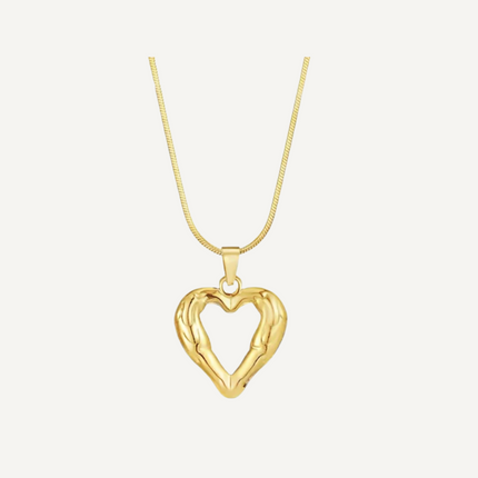 Gold heart-shaped pendant on a chain against a light beige background