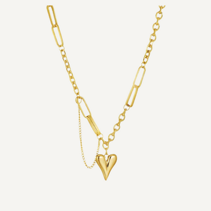 Gold necklace with a heart pendant on a light beige background