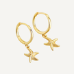 Gold hoop earrings with starfish charms on a light gray background