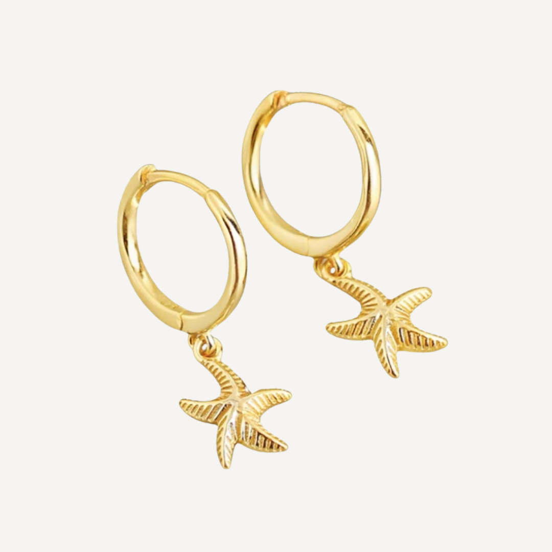 Gold hoop earrings with starfish charms on a light gray background