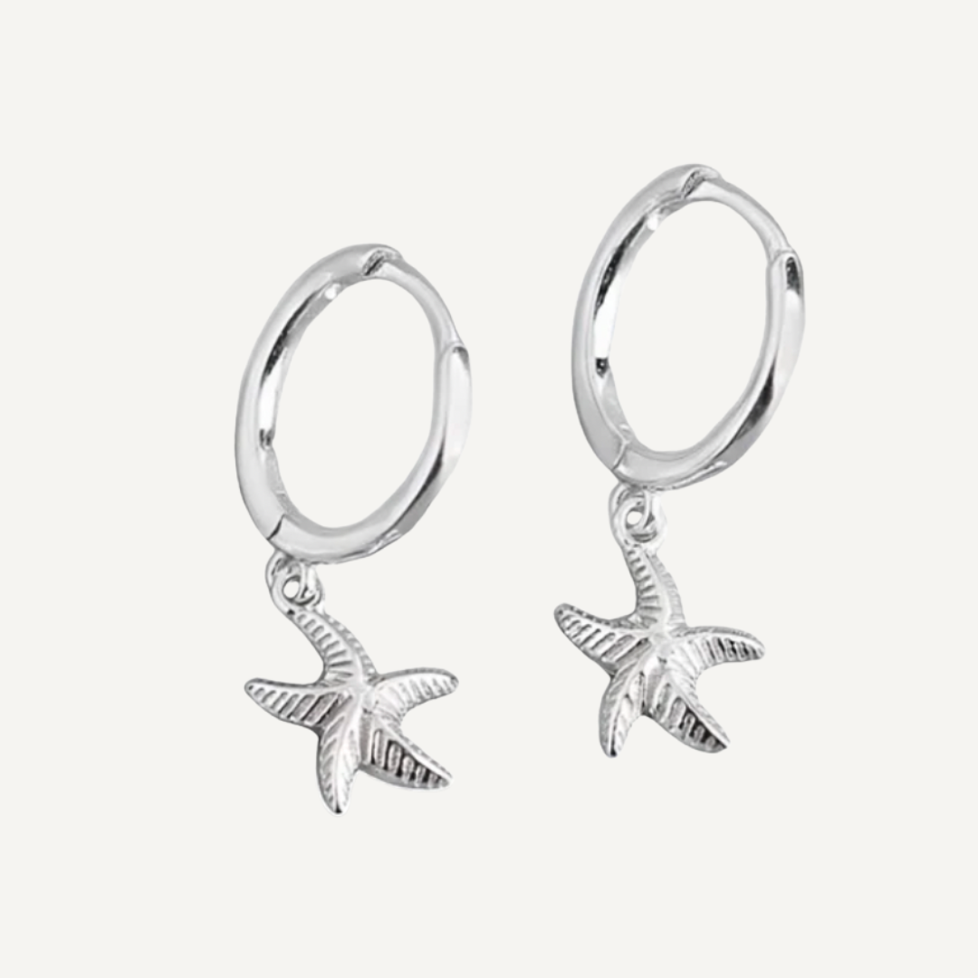 Silver hoop earrings with starfish charms on a light gray background