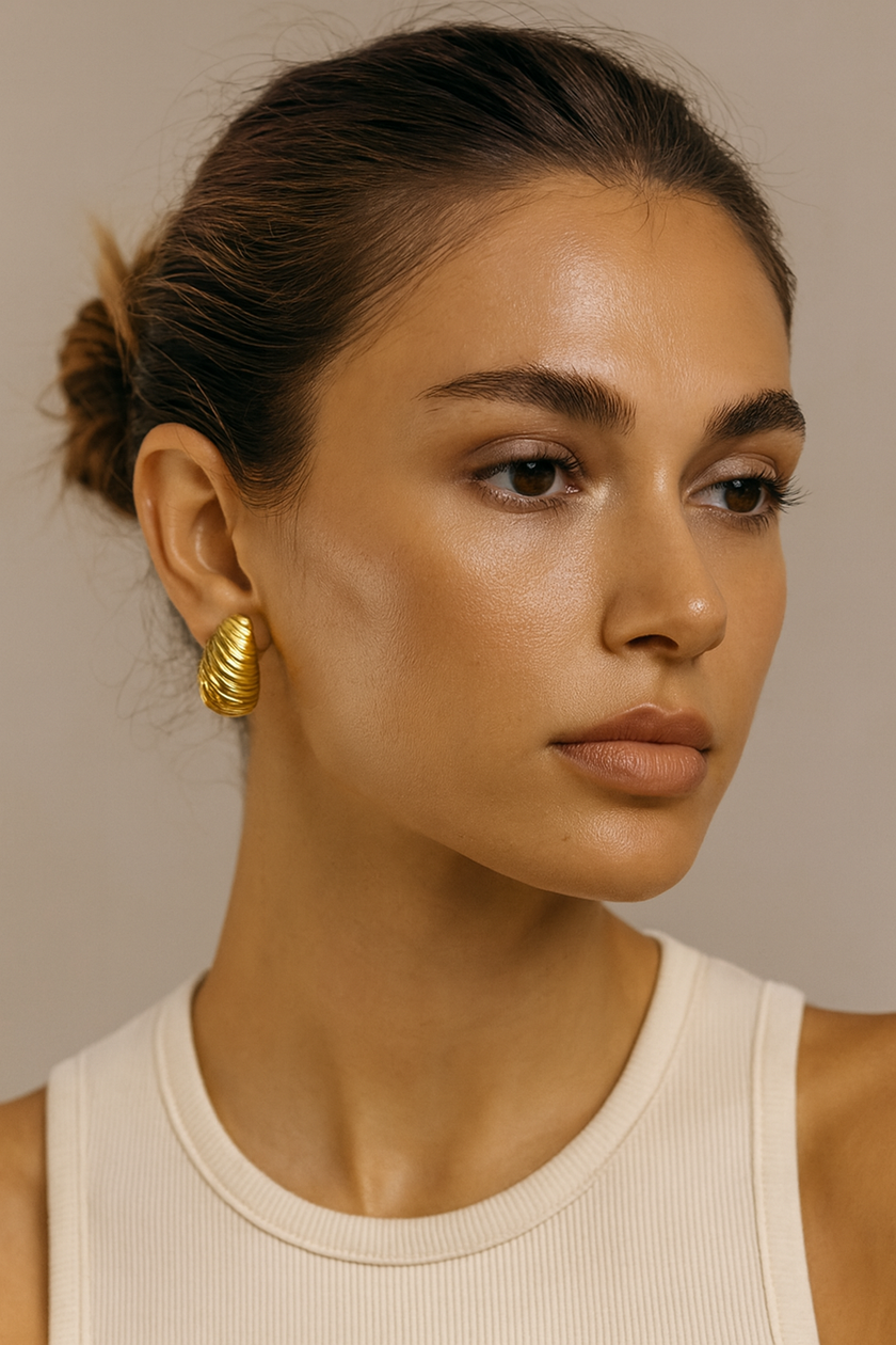 Woman wearing gold hoop earrings against a neutral background